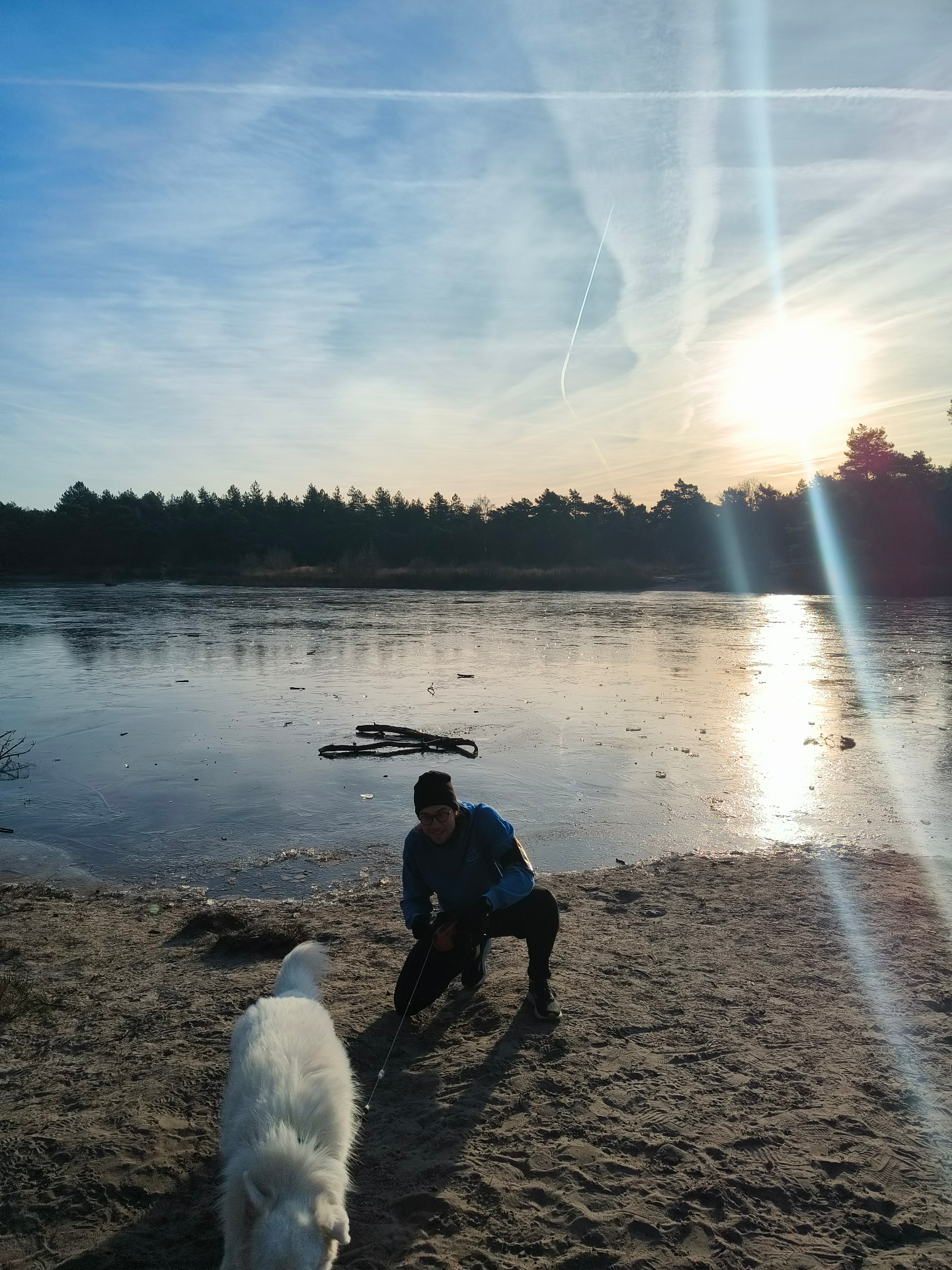 Jori met zijn hond bij een bevroren meer bij zonsopkomst